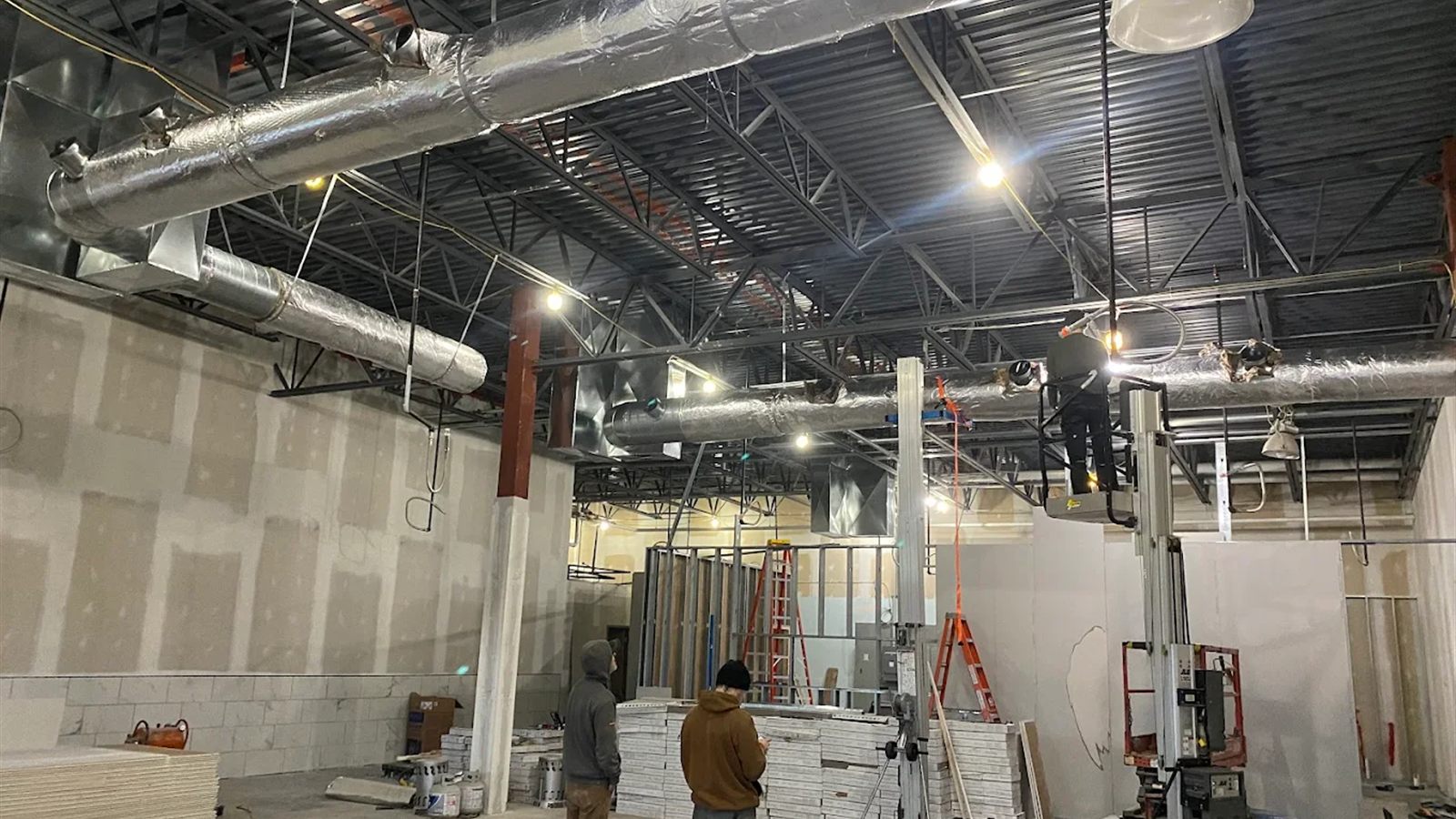 Spiral ductwork being installed above a bar-joist ceiling during a commercial fit-out