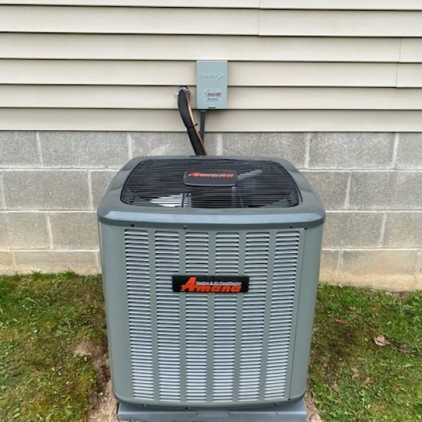 Outdoor air conditioning condenser unit installed beside a residential foundation